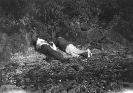 Mary Rattenbury and unidentified man reclined on the beach