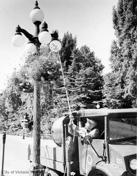 City employee watering hanging baskets