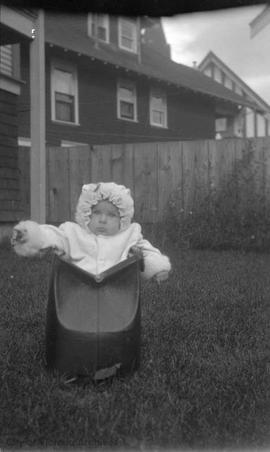 McDonald baby (?) propped up in bag in yard on Raynor Avenue