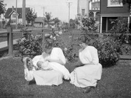 Helen McDonald and baby with family members (?) lounging on the grass on Raynor Avenue