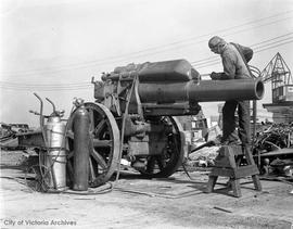 Welder George Taylor cutting up a German field howitzer at Capitol Iron.  The gun was captured at Bourlon Woods in Sept 1918