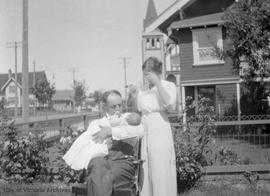 Helen McDonald with family member (?) holding baby in yard on Raynor Avenue